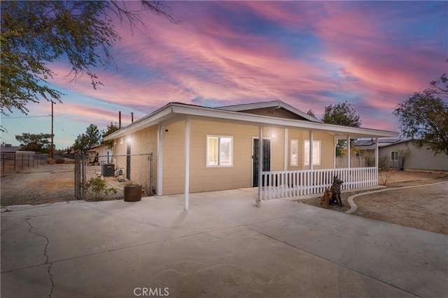 view of front of home featuring covered porch, a gate, fence, and central AC