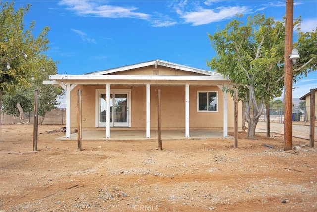 view of front facade with a patio area, fence, and stucco siding