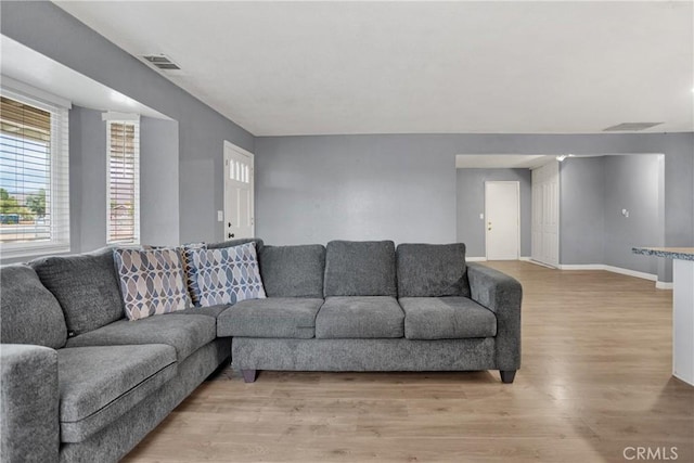 living area with baseboards, visible vents, and light wood-style floors