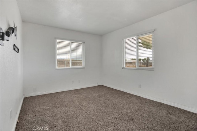 carpeted spare room with a healthy amount of sunlight and baseboards