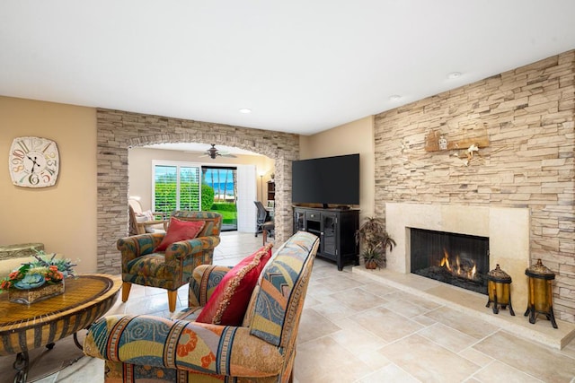 living room featuring ceiling fan and a fireplace