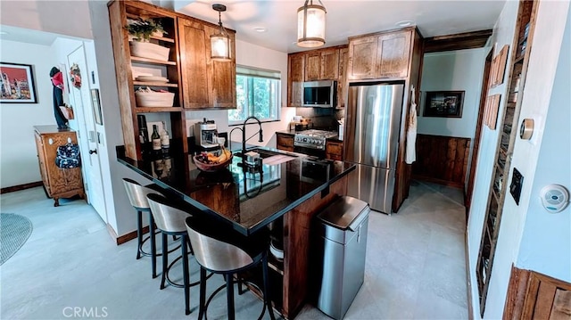 kitchen featuring a breakfast bar, sink, decorative light fixtures, and appliances with stainless steel finishes