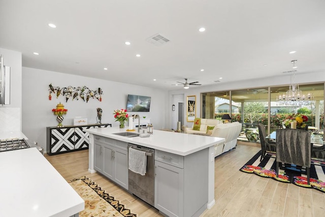 kitchen with appliances with stainless steel finishes, ceiling fan, sink, a center island with sink, and light hardwood / wood-style flooring