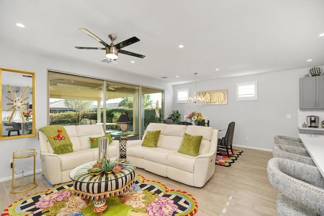 living room with ceiling fan with notable chandelier and light wood-type flooring