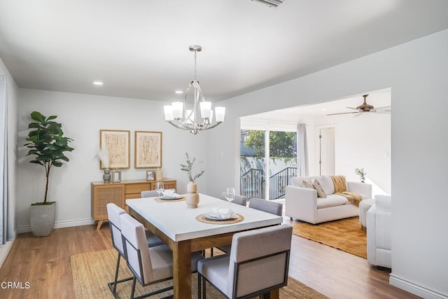 dining area with light wood-type flooring and ceiling fan with notable chandelier