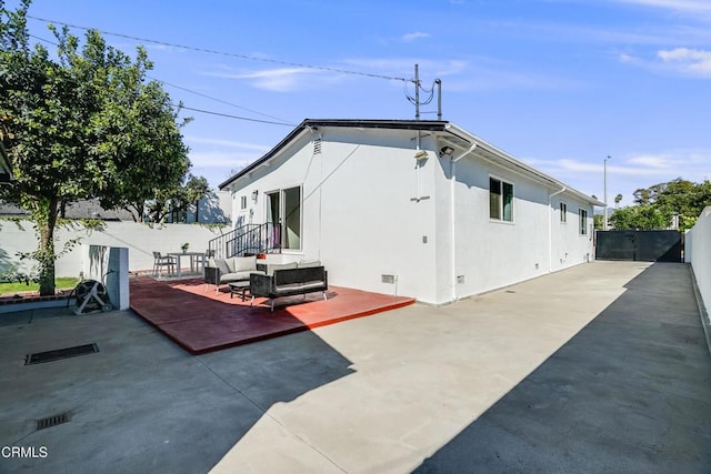 rear view of property with an outdoor living space and a patio area