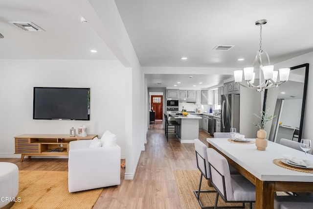 dining space with light wood-type flooring and a notable chandelier