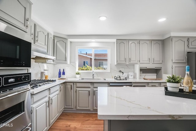 kitchen featuring light wood-type flooring, sink, gray cabinetry, and stainless steel appliances