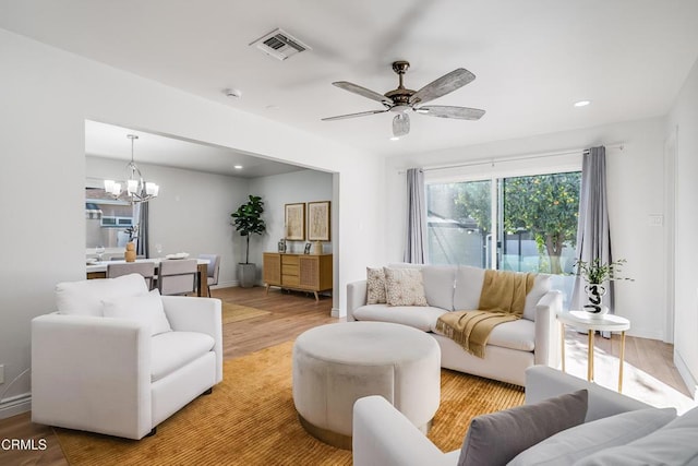 living room with ceiling fan with notable chandelier and hardwood / wood-style flooring