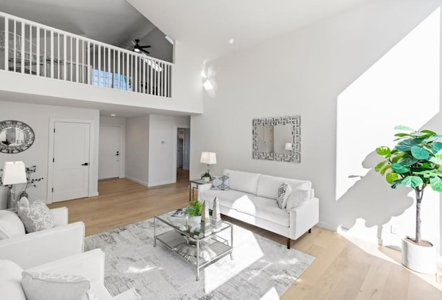 living room featuring light hardwood / wood-style floors, high vaulted ceiling, and ceiling fan