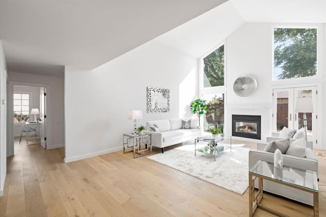 living room featuring light hardwood / wood-style floors, high vaulted ceiling, and french doors