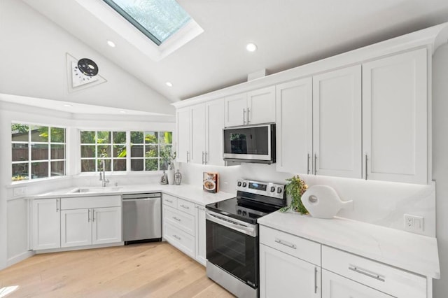 kitchen with white cabinets, vaulted ceiling with skylight, and stainless steel appliances