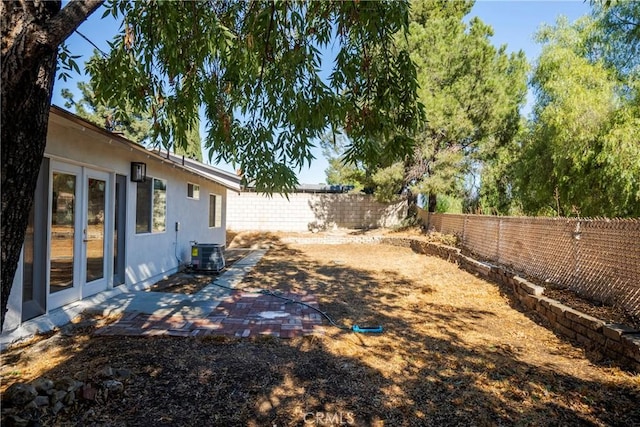 view of yard featuring a patio area, central AC unit, and french doors