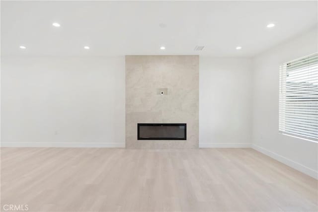 unfurnished living room with a tile fireplace and light hardwood / wood-style floors