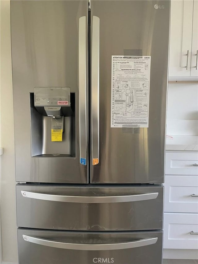 details with stainless steel fridge with ice dispenser and white cabinets