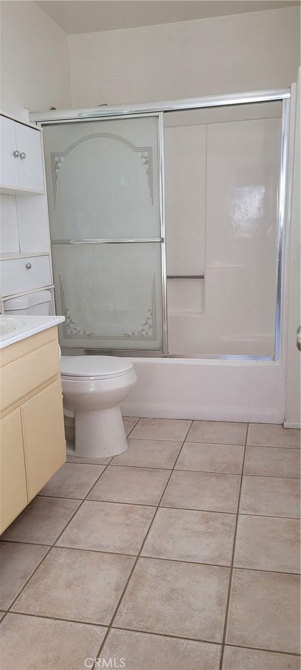 full bathroom featuring tile patterned floors, vanity, toilet, and bath / shower combo with glass door