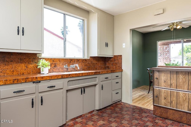 kitchen featuring white cabinets, a healthy amount of sunlight, and backsplash