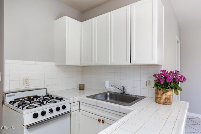 kitchen with gas range gas stove, tile counters, and white cabinets