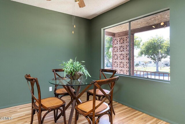 dining space featuring ceiling fan, light wood-type flooring, and a textured ceiling