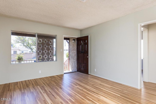 unfurnished room with light hardwood / wood-style floors and a textured ceiling