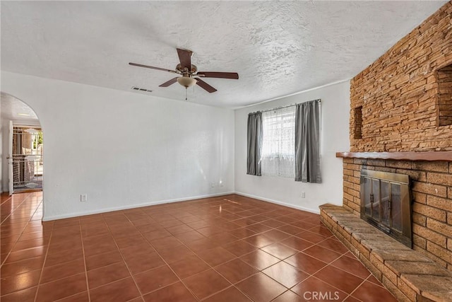 unfurnished living room featuring dark tile patterned floors, ceiling fan, a large fireplace, and a textured ceiling