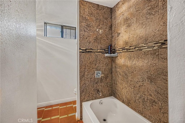 bathroom with tile patterned floors, toilet, and tiled shower / bath combo