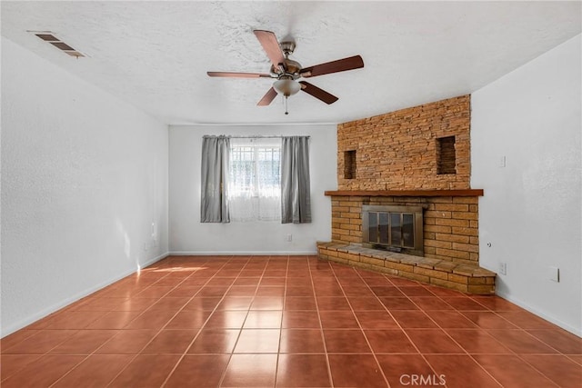 unfurnished living room with ceiling fan, tile patterned floors, a fireplace, and a textured ceiling