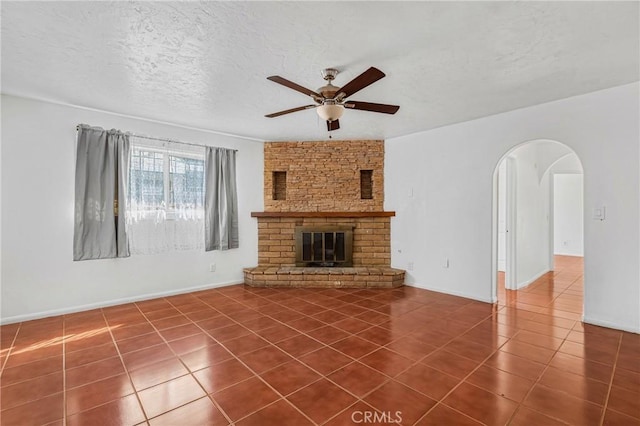 unfurnished living room with tile patterned flooring, ceiling fan, a textured ceiling, and a fireplace