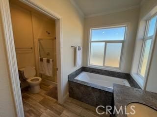 bathroom featuring a garden tub, toilet, ornamental molding, a stall shower, and wood finished floors