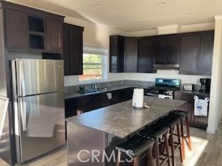 kitchen with under cabinet range hood, a breakfast bar, light wood-style floors, appliances with stainless steel finishes, and a center island