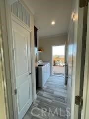 hall featuring hardwood / wood-style floors, ornamental molding, and independent washer and dryer