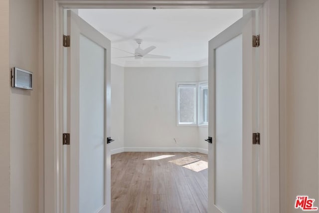 hallway with light hardwood / wood-style floors and crown molding