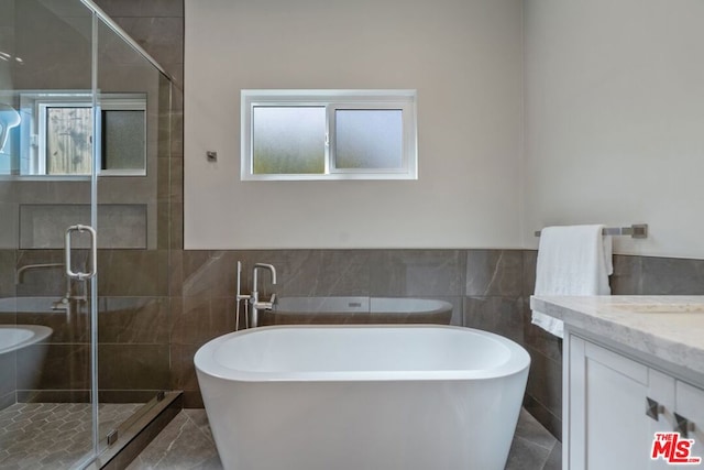 bathroom with vanity, tile walls, and independent shower and bath