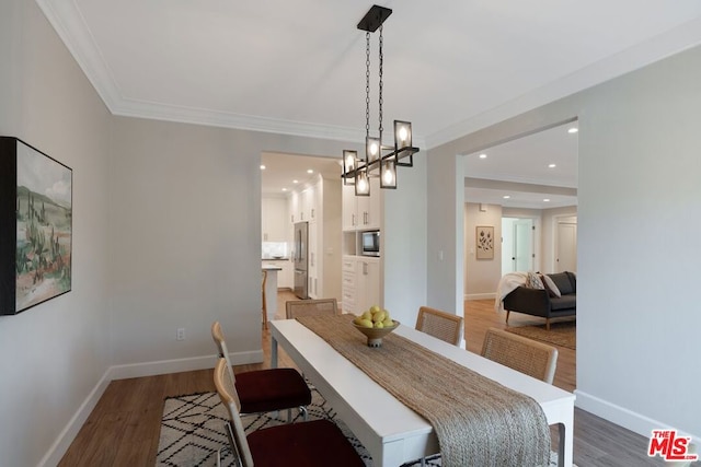 dining space featuring a chandelier, ornamental molding, and dark wood-type flooring