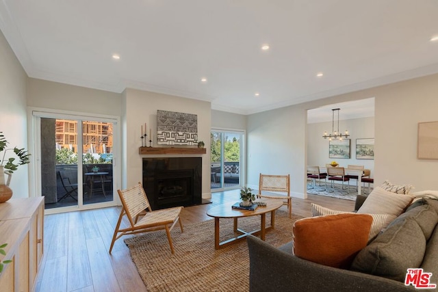 living room with a chandelier, light hardwood / wood-style flooring, a wealth of natural light, and ornamental molding