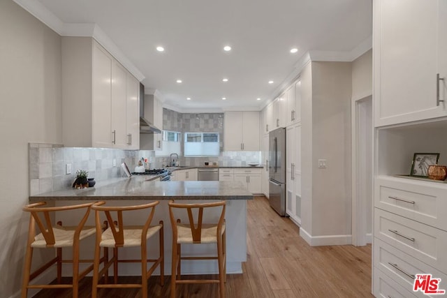 kitchen with a kitchen breakfast bar, light wood-type flooring, white cabinetry, and stainless steel appliances