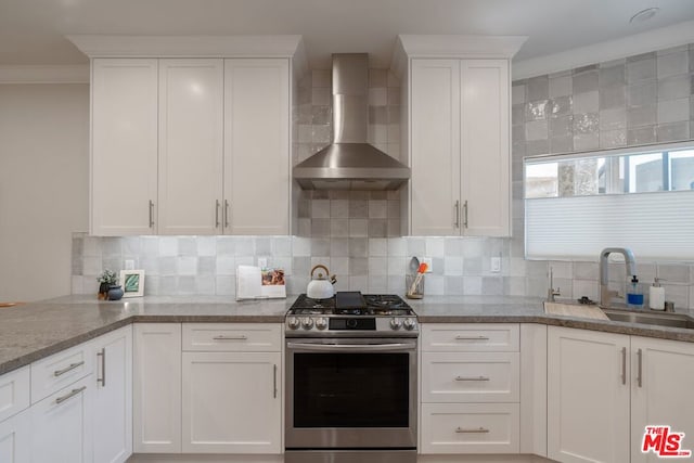 kitchen featuring white cabinets, ornamental molding, stainless steel gas stove, and wall chimney exhaust hood