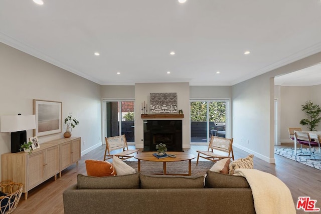 living room featuring a healthy amount of sunlight, light hardwood / wood-style floors, and ornamental molding