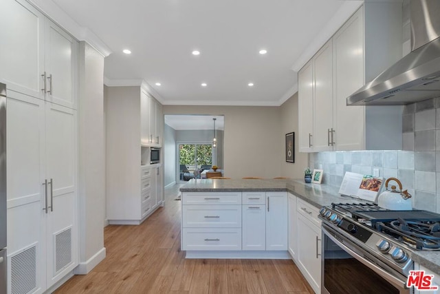 kitchen featuring wall chimney range hood, kitchen peninsula, stainless steel gas range, light hardwood / wood-style floors, and white cabinetry