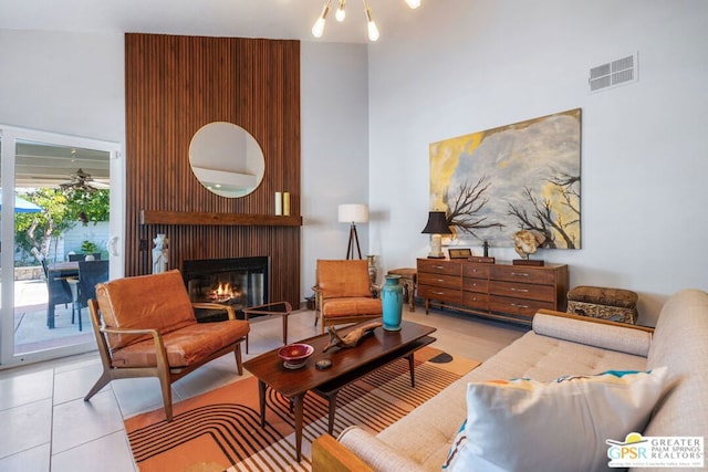 living room with a large fireplace, a high ceiling, and an inviting chandelier