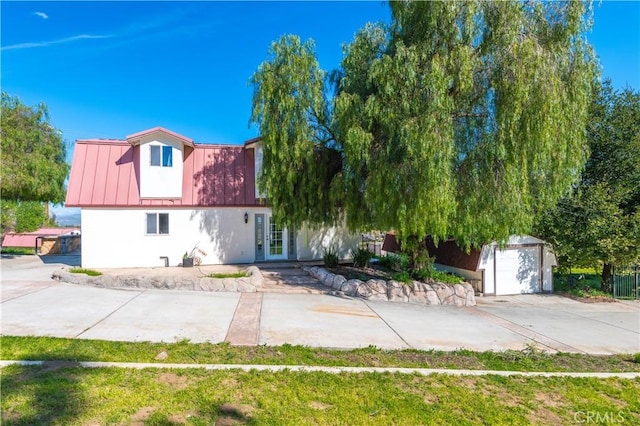 view of front of property with a garage, an outdoor structure, and french doors