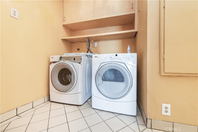 clothes washing area with washing machine and dryer and light tile patterned floors