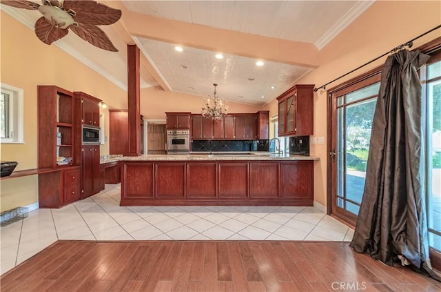 kitchen featuring kitchen peninsula, appliances with stainless steel finishes, vaulted ceiling with beams, and light hardwood / wood-style flooring