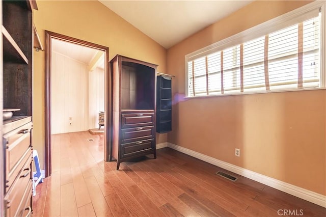 unfurnished bedroom featuring hardwood / wood-style flooring and vaulted ceiling