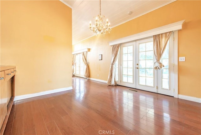 unfurnished living room with a chandelier, french doors, wood-type flooring, and ornamental molding