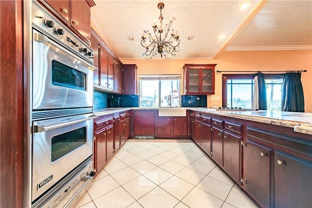 kitchen with light tile patterned floors, a textured ceiling, decorative light fixtures, stainless steel double oven, and a chandelier