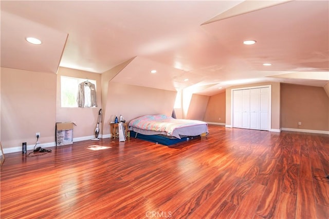 bedroom featuring hardwood / wood-style floors, vaulted ceiling, and a closet