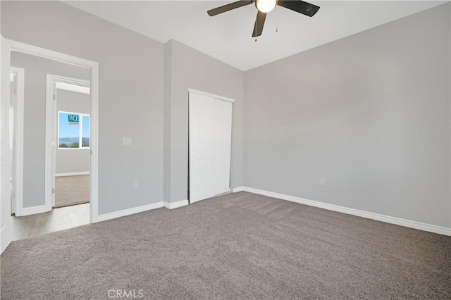 unfurnished bedroom with ceiling fan, a closet, carpet, and vaulted ceiling