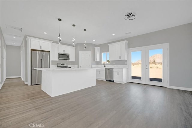 kitchen with white cabinetry, hanging light fixtures, a center island, and stainless steel appliances