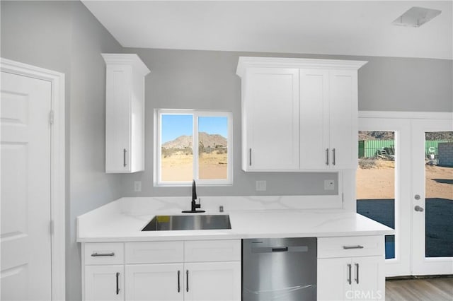 kitchen with dishwasher, white cabinetry, and sink